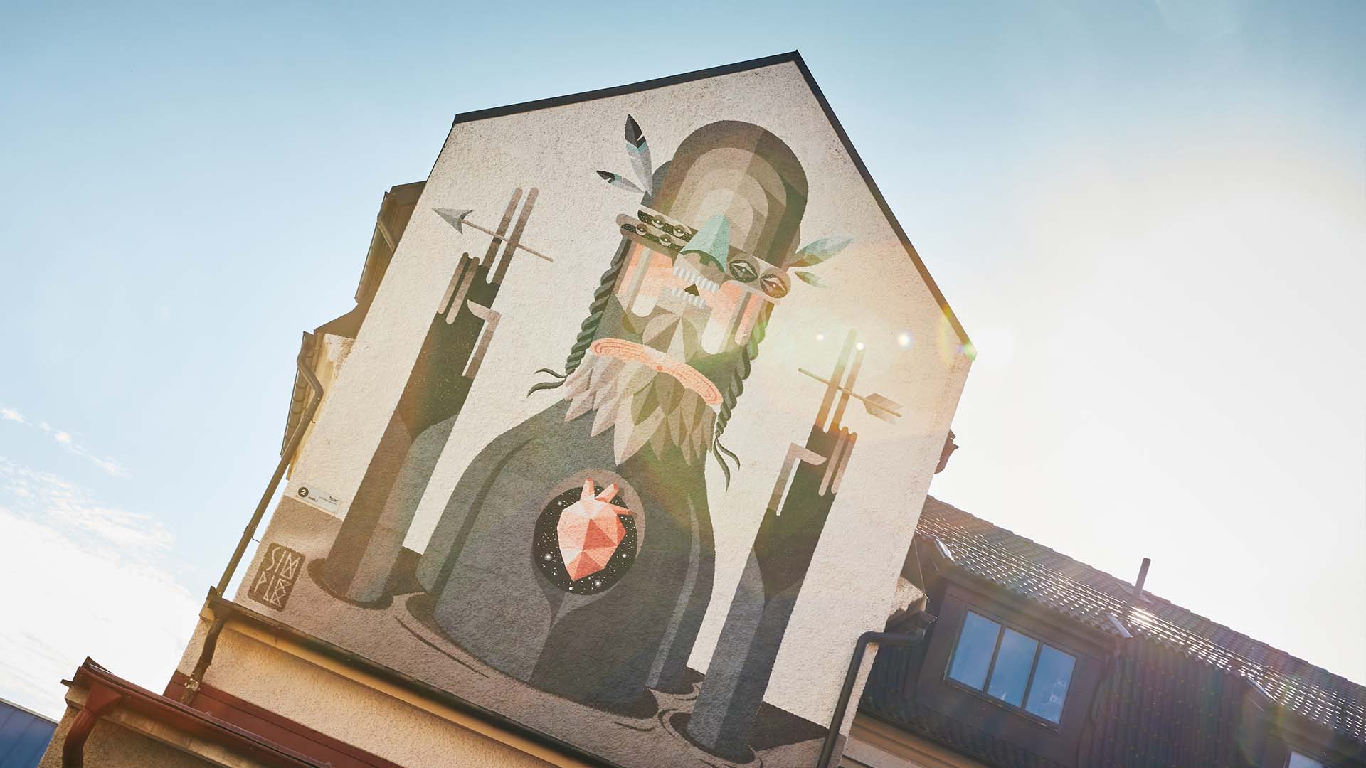 Muralmålning i beiga och gråa färger av en figur med ett öppet hjärta