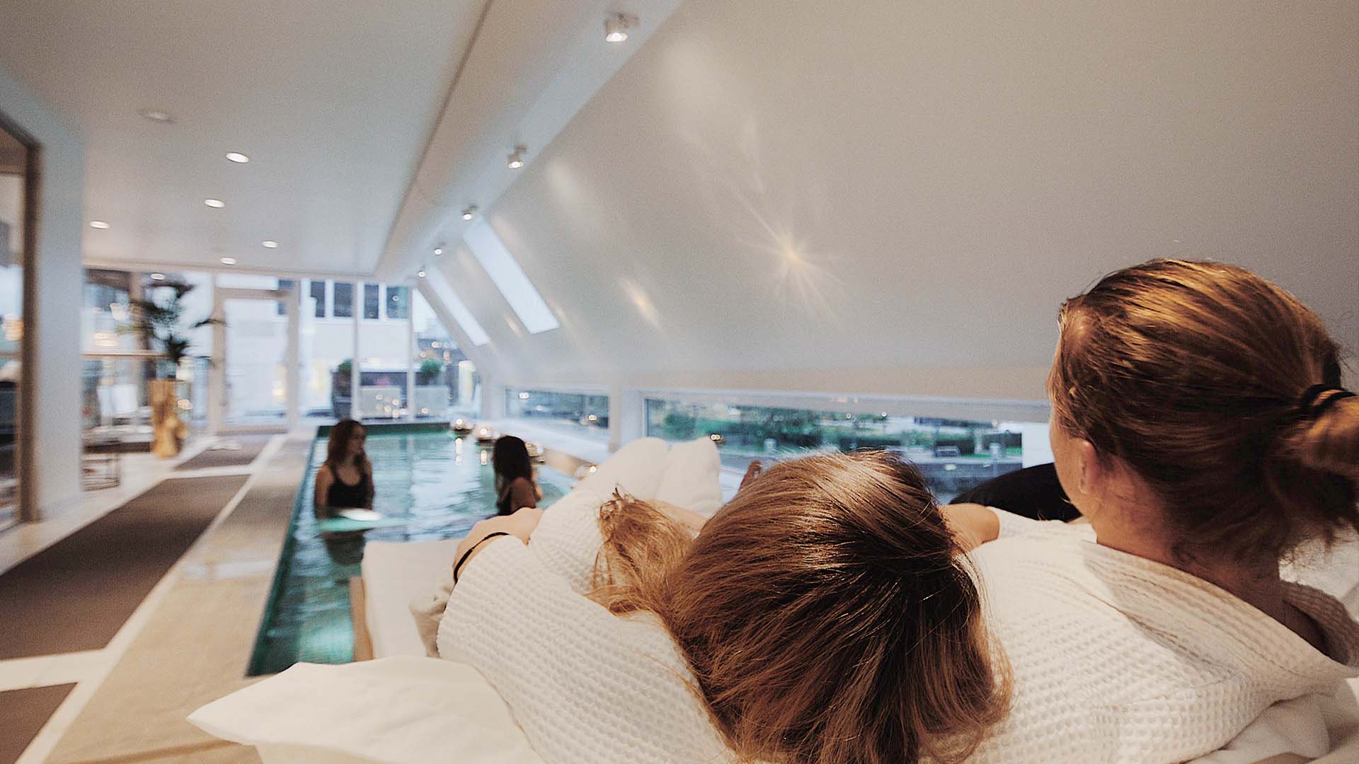 Ett par ligger i en loungesäng vid en inomhuspool