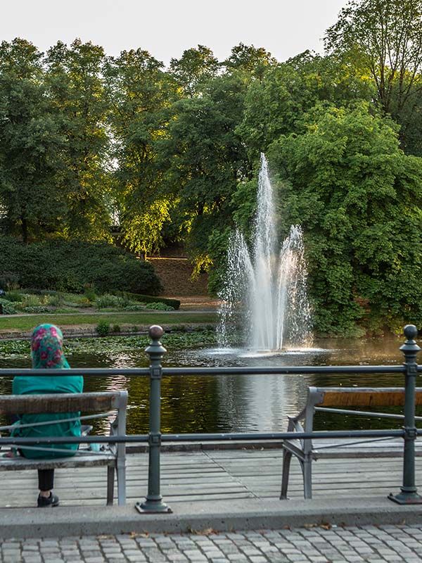En kvinna sitter på en bänk i den grönskande parken
