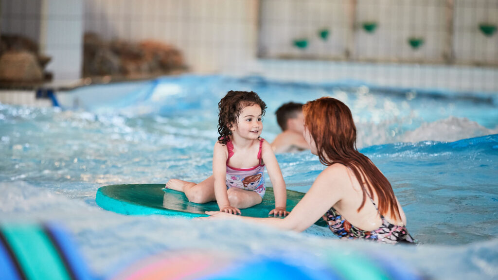 Mamma och barn badar i vårbassängen i Stadsparksbadet