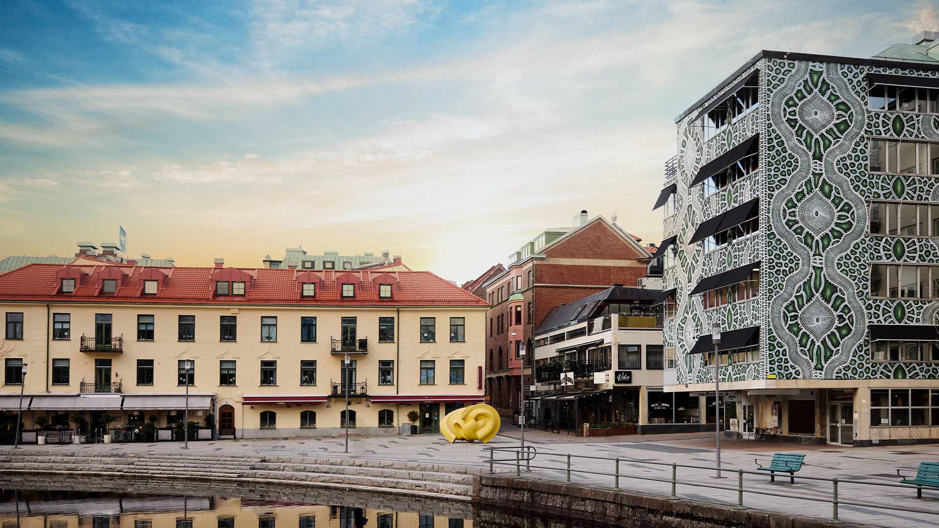 En stadsvy där en byggnad har en muralmålning i grönt och vitt.