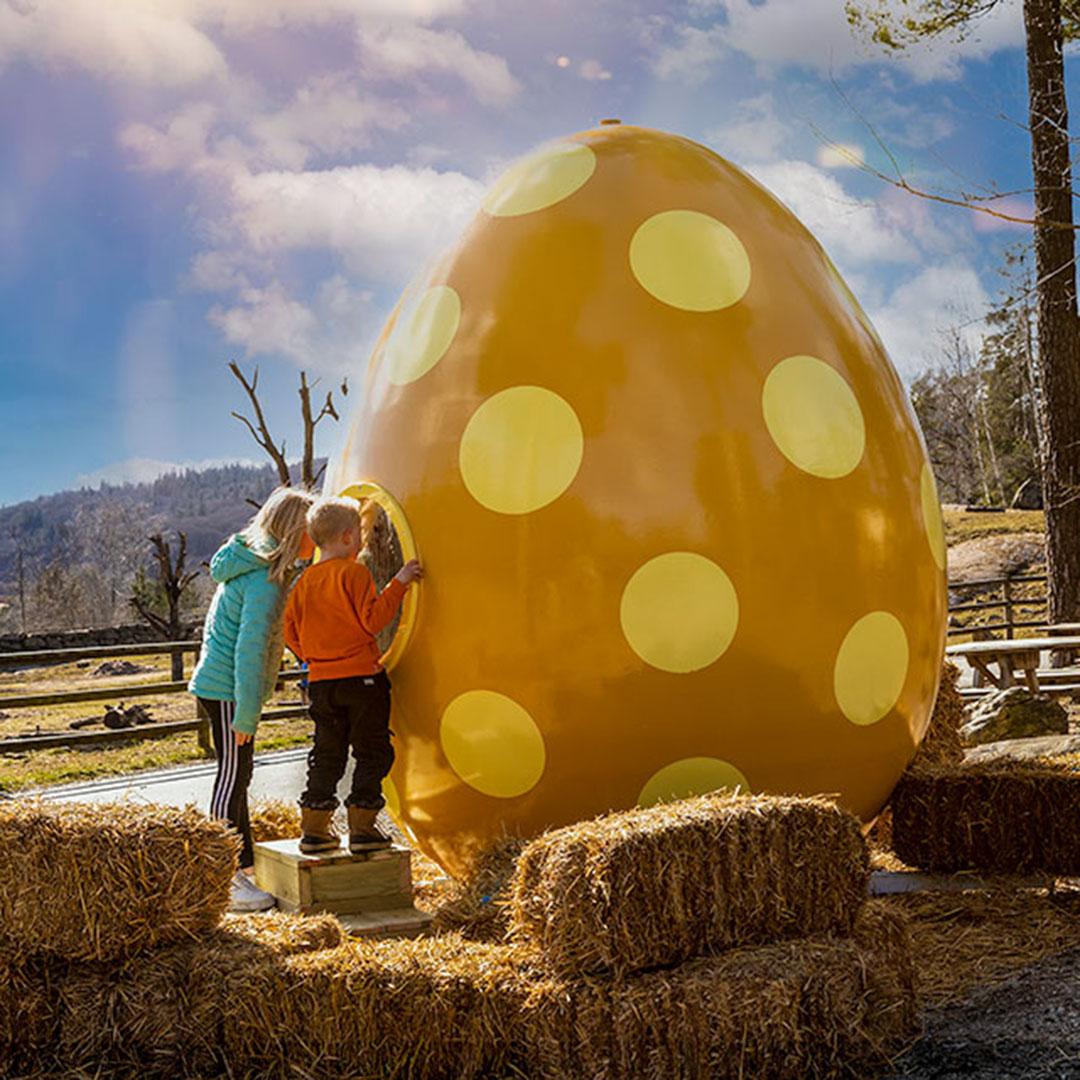 Två barn tittar in i ett jättestort påskägg.