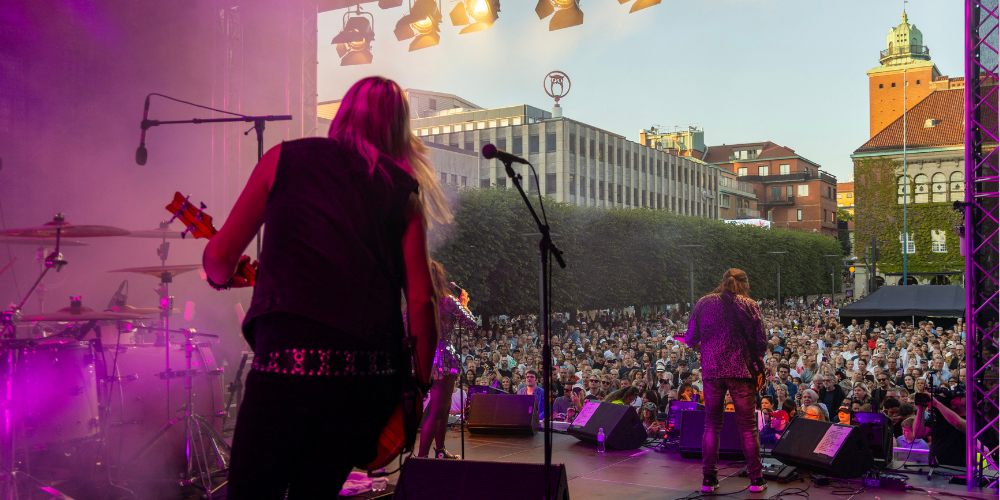 Ett band spelar musik framför ett torg fyllt av folk.