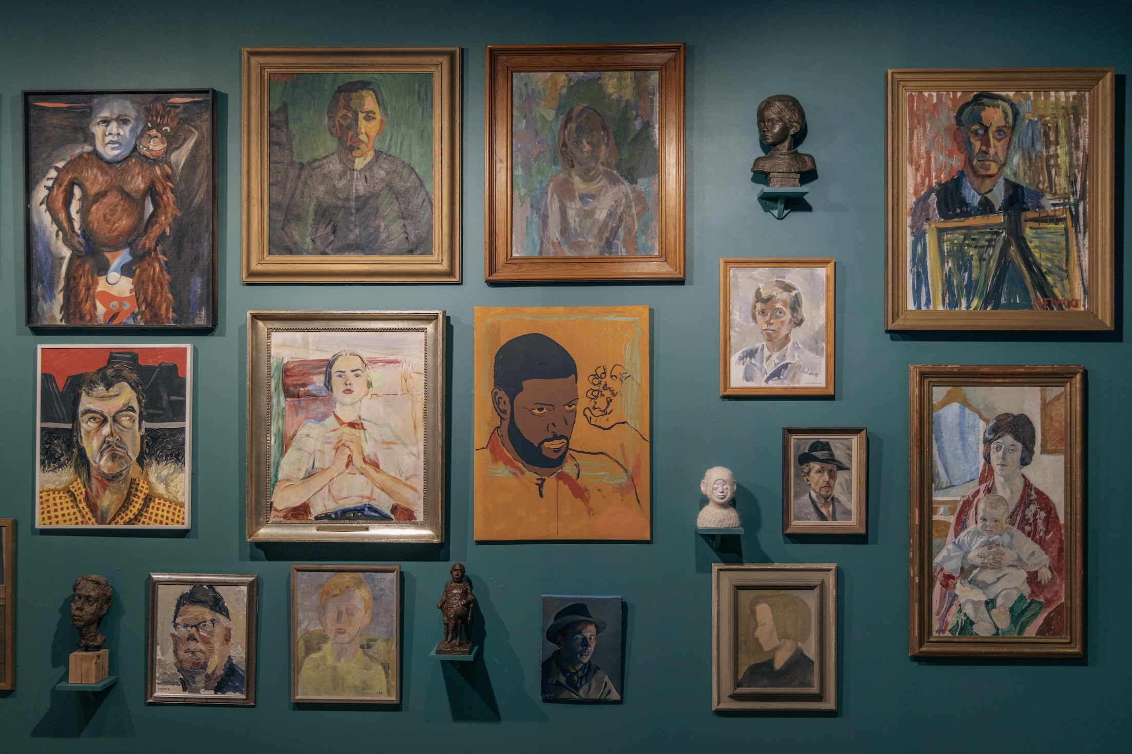 En grön vägg med en massa målningar på.