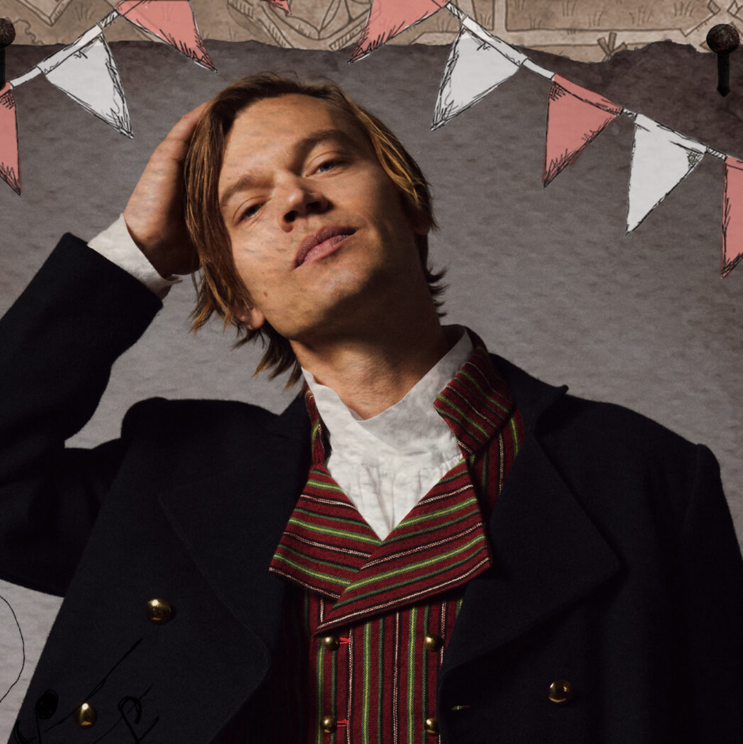 en artistbild, en man i svart rock och rödrandig kavaj